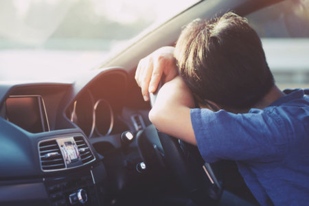 Drunk young man slumped on steering wheel be tired sleep in car driving.