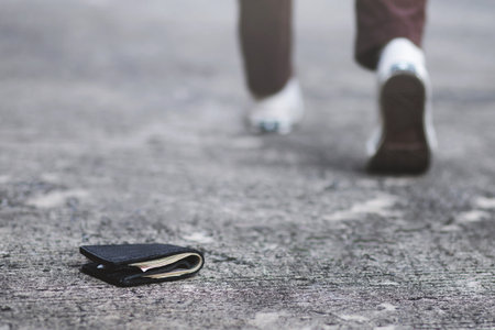 people young man had lost leather wallet with money on the street. Close-up of wallet lying on the road concrete sidewalk in during the trip to travel.の写真素材