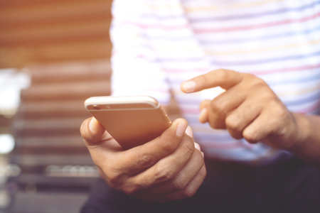 Young male casual wear using on cell phone during rest on sofa. sitting in watching message on mobile phone during break relax.の写真素材