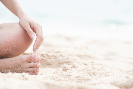 young woman sitting in relaxation outdoors on tropical beach with sand, body parts. Tanned sunbath girl in Lotus position yoga relax, and meditation. summer travel holiday concept.の写真素材