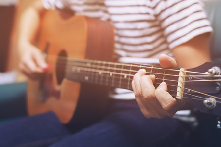 Stylish hipster guy Acoustic Guitar Playing by hand. Artist young male musician Plaid shirt Playing...