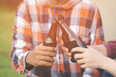 Traveling two young Friends having fun together Relax in hiking camp and drinking beer Cheers bottles And Enjoying. Vacation Travel Adventure Concept. mountain forest river view background.の写真素材