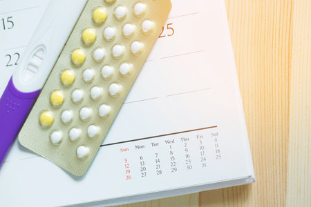 positive pregnancy test and contraceptive control pills on date of calendar on the table wood background. health care and medicine Birth control concept.の写真素材