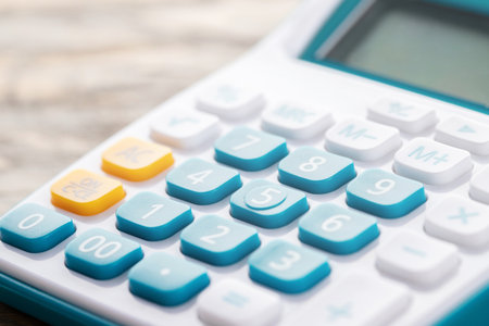 calculator focus at on press button keyboard. calculator colors blue yellow and white on wood table. concept calculate account finance.の写真素材