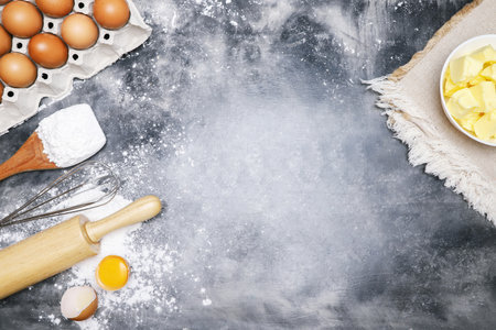 dough preparation recipe bread. Baking ingredients bakery cooking. butter on sackcloth, egg and flour on black board. flat lay on table Bare mortar cement style loft background. Top view, copy space.の写真素材