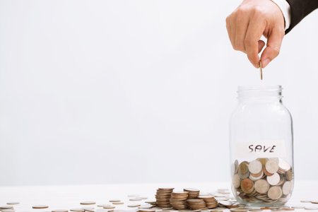 close up hand business man accounting with savings money coins stacked row with hand putting coins in jug glass.の写真素材