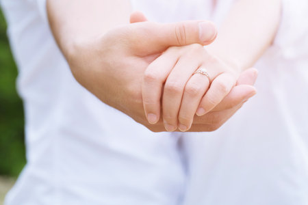 Loving Young love married couple holding hand and a ring together in ceremony wedding day marry scene propose. couple be hand in hand promise or swear. Shake hand with rose flower bouquet.の写真素材