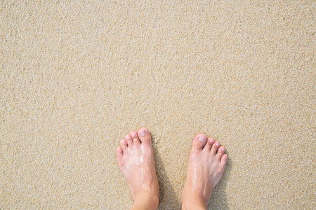 Closeup of a man's bare feet stand at wet on the beach , with a wave's edge foaming gently beneath them. Vacation on ocean beach, foot on sea sand. Leave empty copy space Enter the text above.の写真素材