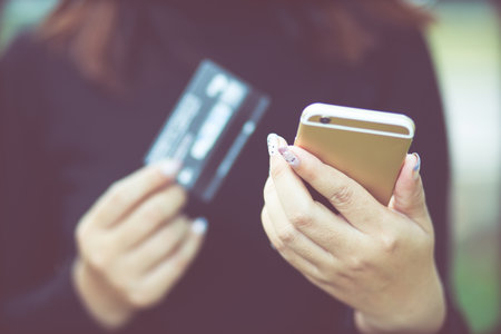 female hands holding credit card and using phone. Online shopping purchase Sell or Payment. filler vintage.の写真素材