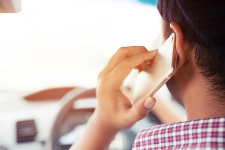 Portrait of young man driving car and speaking talking on mobile phone.