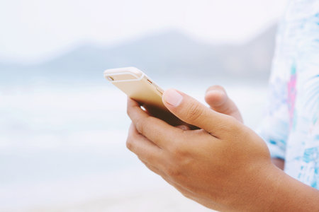 Close up of a man hand holding using mobile smart phone outdoor cellphone on the beach and Mountain....