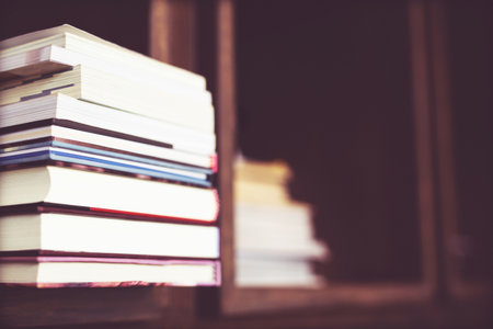 Books are placed on a wooden table and bookshelf in a library. education concept. with filter Tones retro vintage warm effect.の写真素材