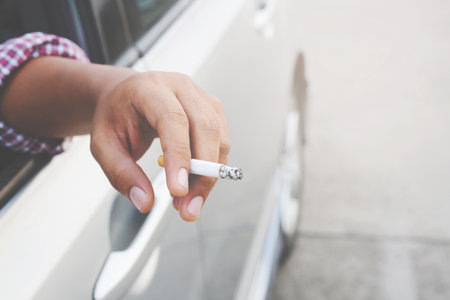 close up hand smoking a cigarette in car.の写真素材