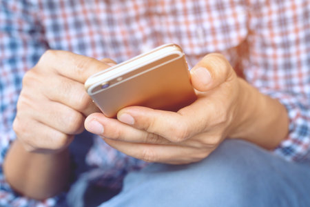 Young business man plaid shirt using on cell phone during rest in office. sitting sofa in watching message on mobile phone during break.の写真素材