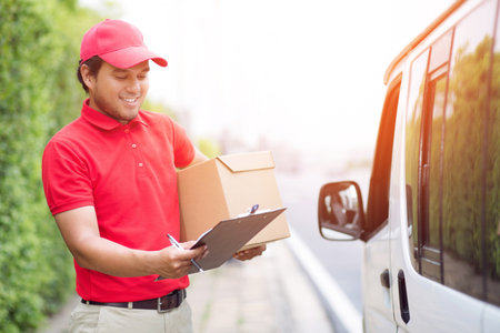 parcel delivery man of a package through a service. and close up hand customer accepting a delivery of boxes from delivery man postal send direct to home.の写真素材
