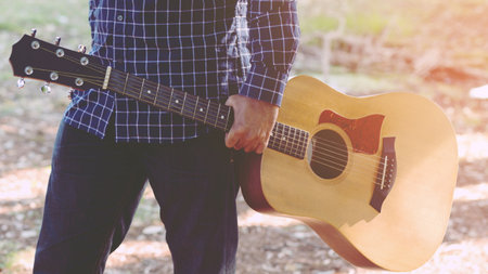 Acoustic guitar guitarist playing. Musical instrument with performer hands in parks.の写真素材