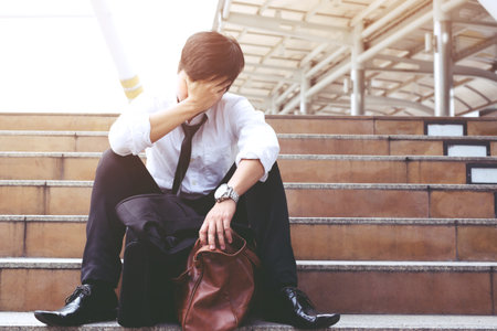 Businessman with briefcase sitting on a ladder. stress people compression in office feel stressful or depression situation Stress cause mental problems Stress and Jobless Concept.の写真素材