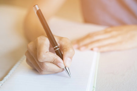 Top view close up hand woman are writing notepad down cost into the book on the sofa.の写真素材
