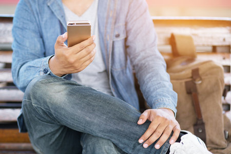 Young male using on cell phone during rest in office. sitting in watching message on mobile phone during break.の写真素材