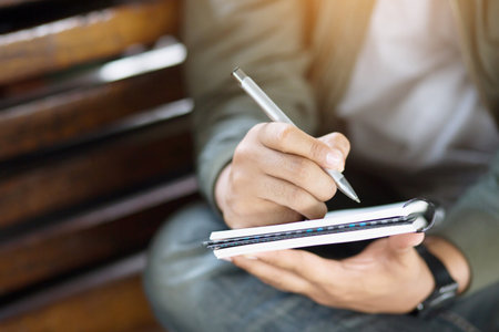 Woman freelancer working hand writing journal on small notebook notepad in coffee shop using with copy space area.の写真素材