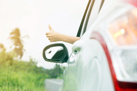 Atmosphere air is refreshing in the sunshine. Young woman hand show thumbs up Drive out on the road on holiday.の写真素材