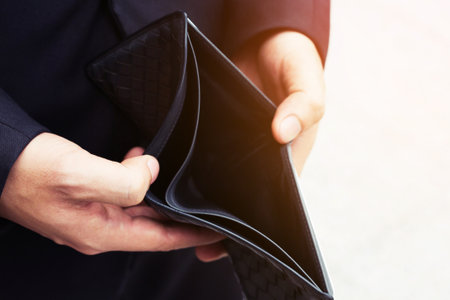 Empty wallet (no money) in the hands of an businessman. High cost of living in city Cost control expenses poverty in concept.の写真素材