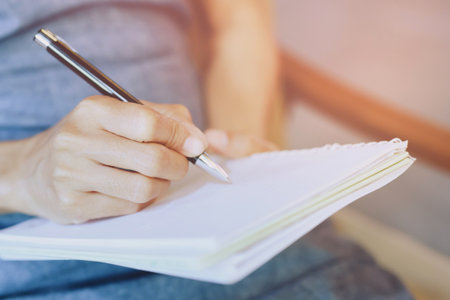 close up hand woman are writing notepad down cost into the book sit on the sofa.の写真素材