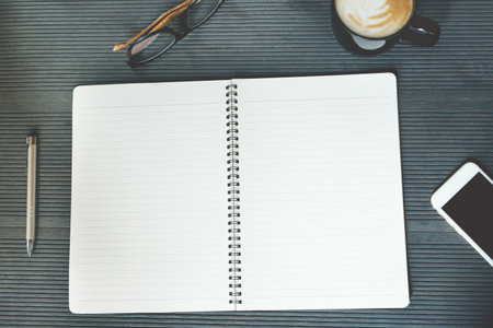 close up business woman hand holding in pen open the page notepad Office desk table with book, equipment supplies in the work spectacles and coffee cup. Top view with copy space on the page paper.の写真素材