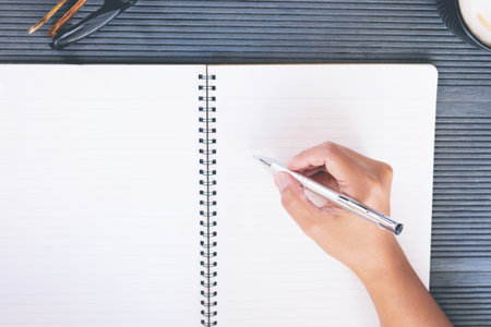close up hand young man are sitting using pen writing Record Lecture notepad into the book on the tableの写真素材