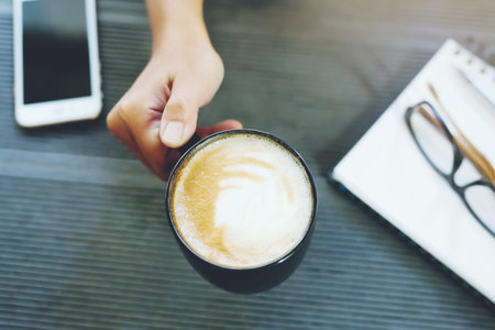 Woman freelancer working hand writing journal on small notebook notepad in coffee shop using with copy space area.の写真素材