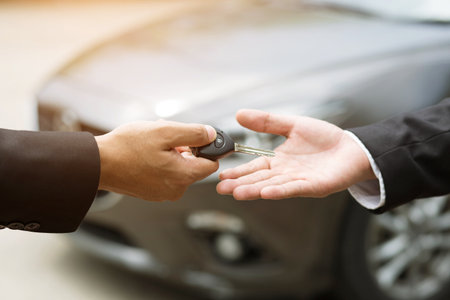 Car key, businessman handing over gives the car key to the other man on car background.の写真素材