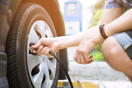 close up hand man car parking a check the tire fill up the air for safe driving on the go.の写真素材