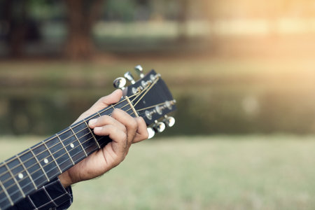 Acoustic guitar guitarist playing. Musical instrument with performer hands in parksの写真素材