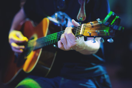 Acoustic guitar guitarist playing. Musical instrument with performer hands on stage in Concert.の写真素材