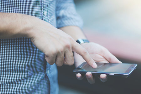 Back view of a close up of Young Man using mobile smart phone.