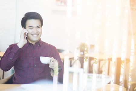 Handsome Business man in an using telephone in coffee shop.の写真素材