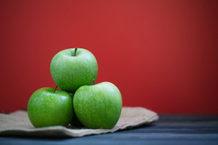 Group of green apples with fresh on a sack in a wooden desk and Red background.の写真素材