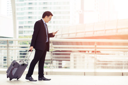 Businessmen are traveling with luggage and using phone contact business.の写真素材