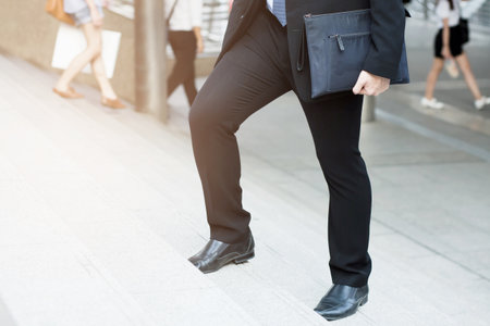businessman legs walking the stairs in modern city.