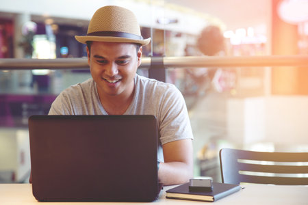 Young man Look focus at the screen computer Connect online business using laptop. or Sitting work at cafe.