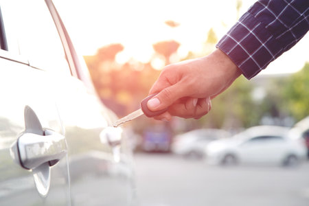 Cropped view of Closeup of a man's hand inserting key into the door lock of a carの写真素材