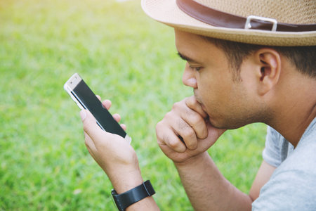 Young Man wear hat sit using mobile smart phoneの写真素材