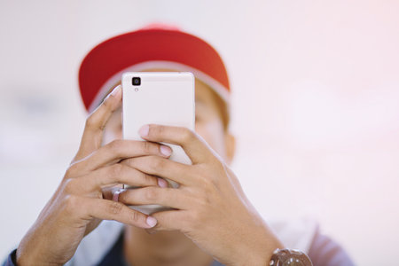 Man wearing red hat playing mobile smart phone.or using phone Taking picturesの写真素材