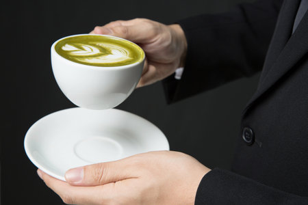 Close up men wear a suit, holding a cup of green tea in hand.