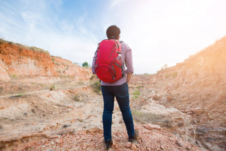 Young travel red backpack enjoying a looking at Mountain abyss , Panoramic view. Traveling along , active lifestyle concept.の写真素材