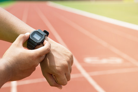 Athlete checking his watch Race timer runner ready to run on running track.の写真素材