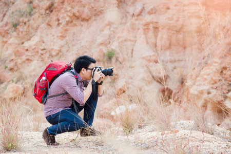 Young photographer travel red backpack enjoying a looking at Mountain abyss , Panoramic view. Traveling along , active lifestyle concept.の写真素材