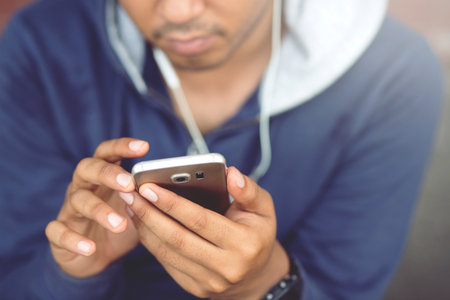 Always in touch. Cheerful handsome young man using Earphone his smart phone.の写真素材