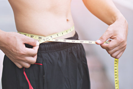 Young sporty man Check body with measuring tape outdoor.Close up, concept of healthy and sport.の写真素材
