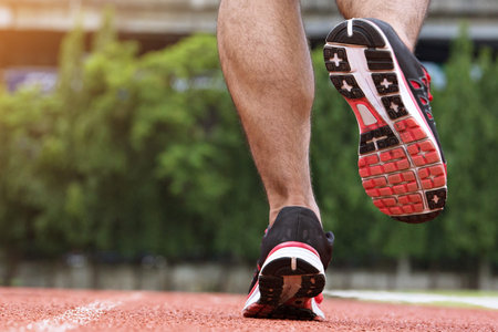 Athlete runner feet running on racetrack closeup on shoe. man fitness jog workout wellness concept.の写真素材